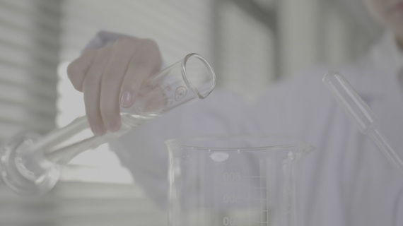 实验室科研人员将量杯液体倒入烧杯特写
